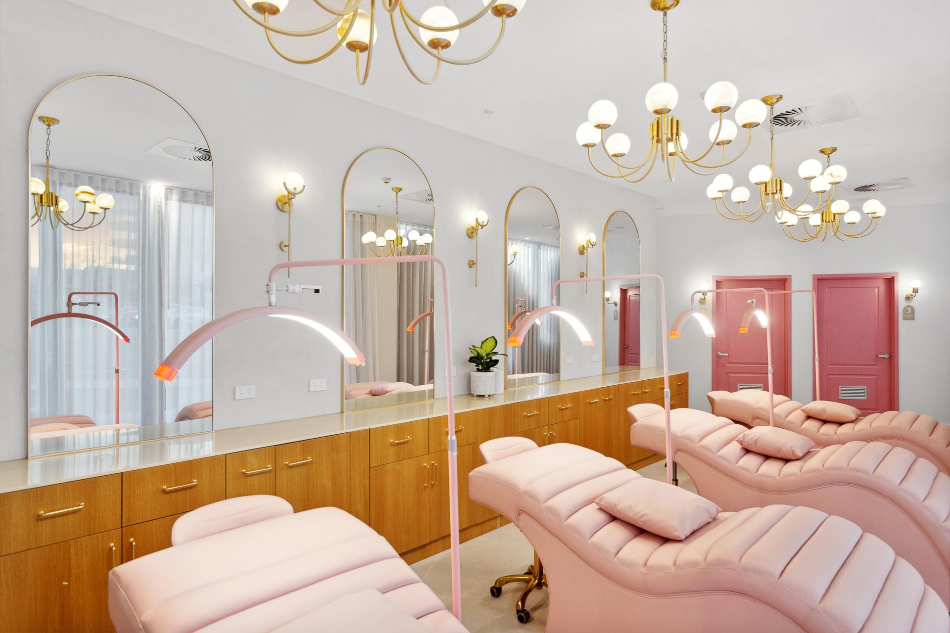 Luxury fiout of Posh Deluxe which features pale pink recliners, gold light fixtures, large mirrors and wooden cabinetry.