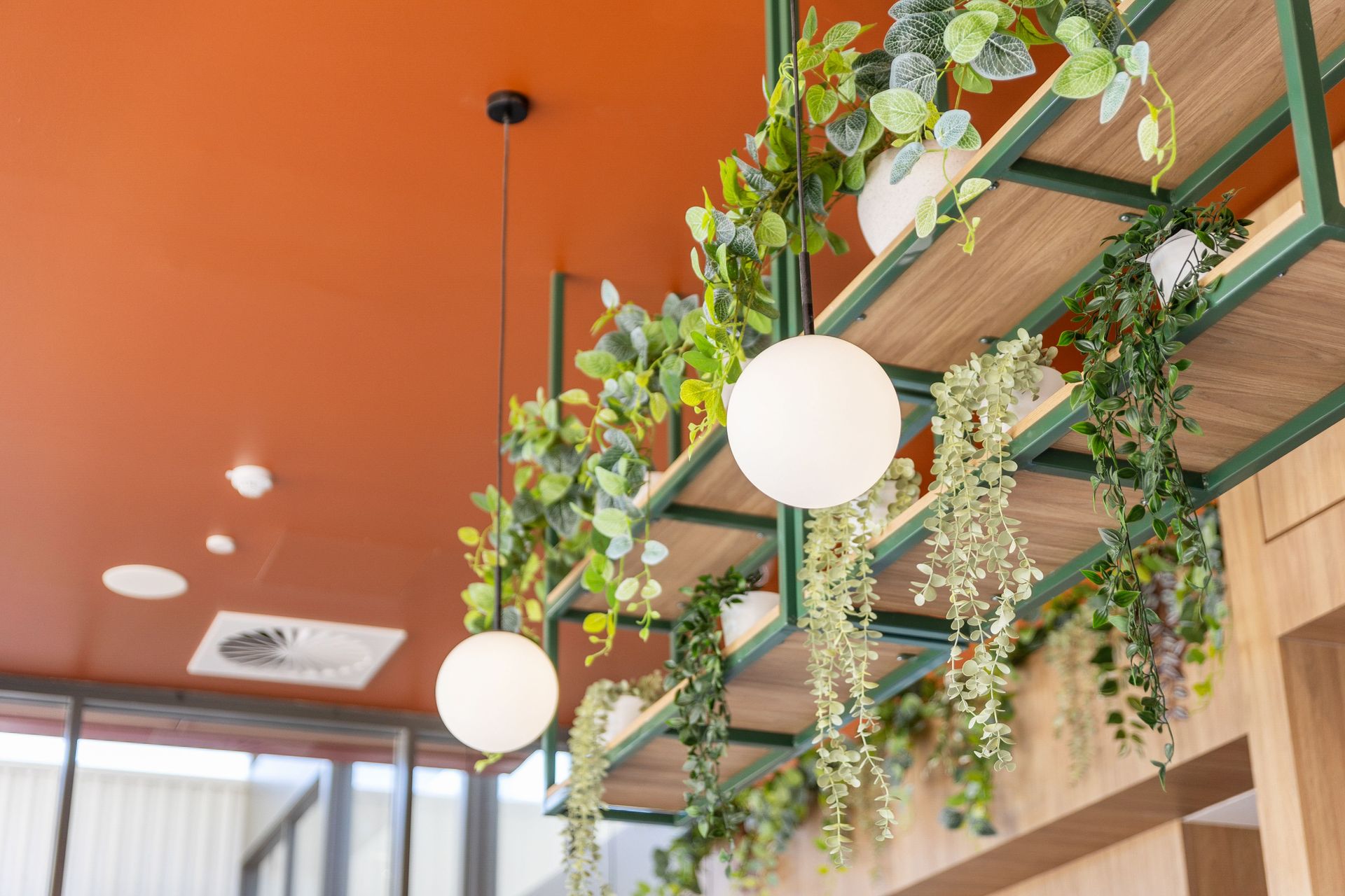 a cafe featuring rich burnt orange walls, wooden cabinetry and plants, showcasing key commercial design trends for 2026